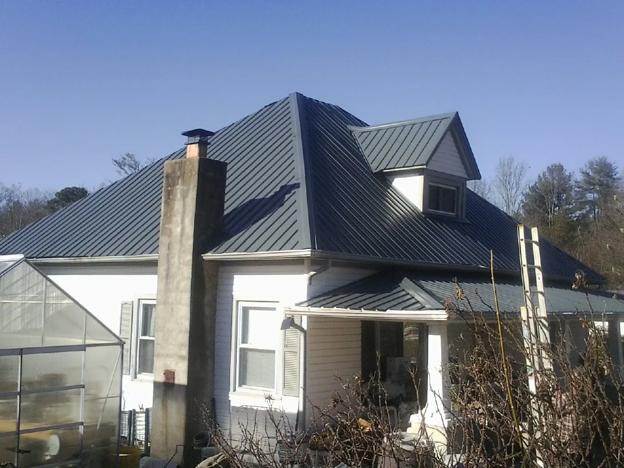 Dark blue standing seam metal roof on a white farmhouse with dormer — Slate & Tile Roof Repair by Roofing Brothers in Bay Minette