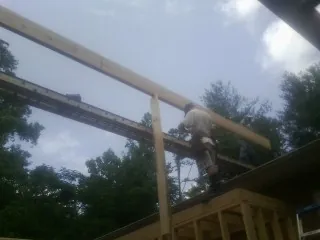 Carpenter setting a ridge beam over a new addition frame — Ice Dam Removal by Roofing Brothers in Bay Minette