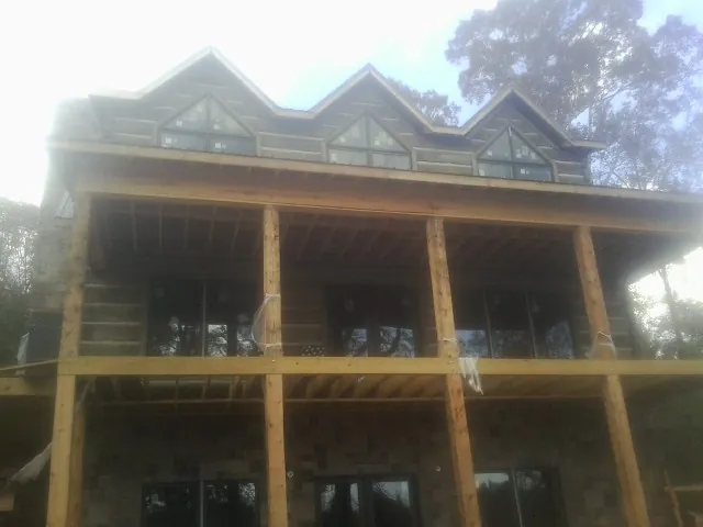 Dormers and porch framing on a large log home under construction — Roof Coating work by our crew in Bay Minette