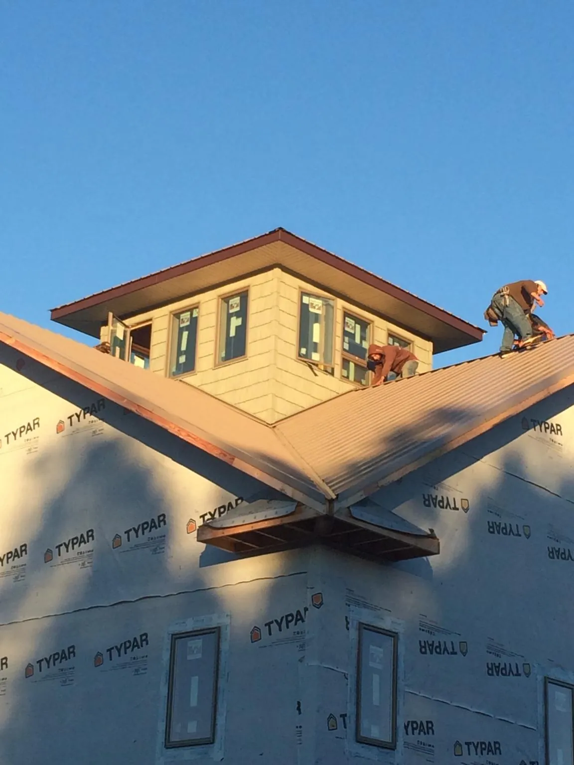 Roofers working around a rooftop cupola on a new metal roof at sunset — Roof Waterproofing in Bay Minette by Roofing Brothers
